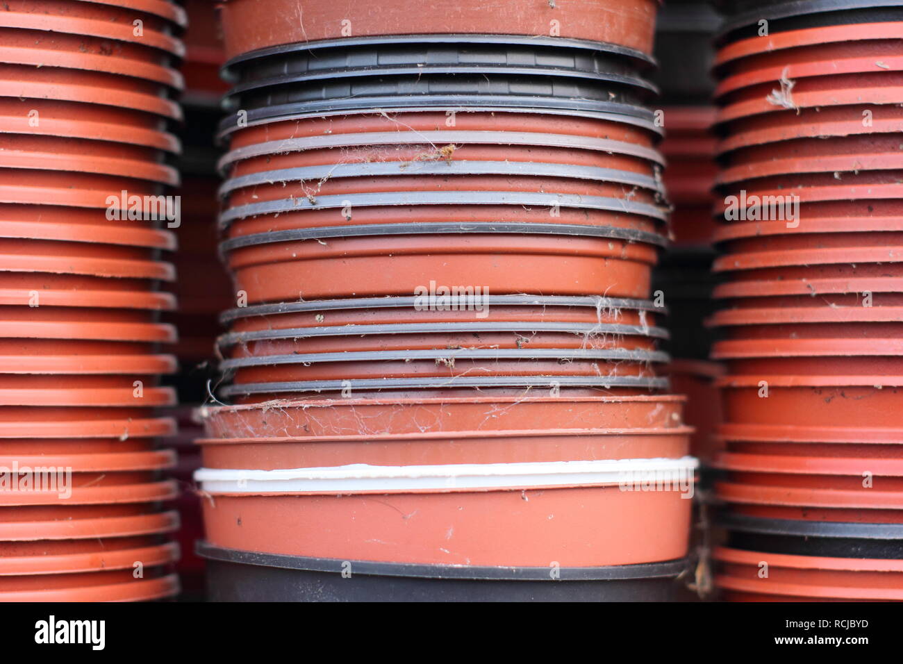 Black and red plastic plants pots in a UK garden. Plastic free gardening concept Stock Photo