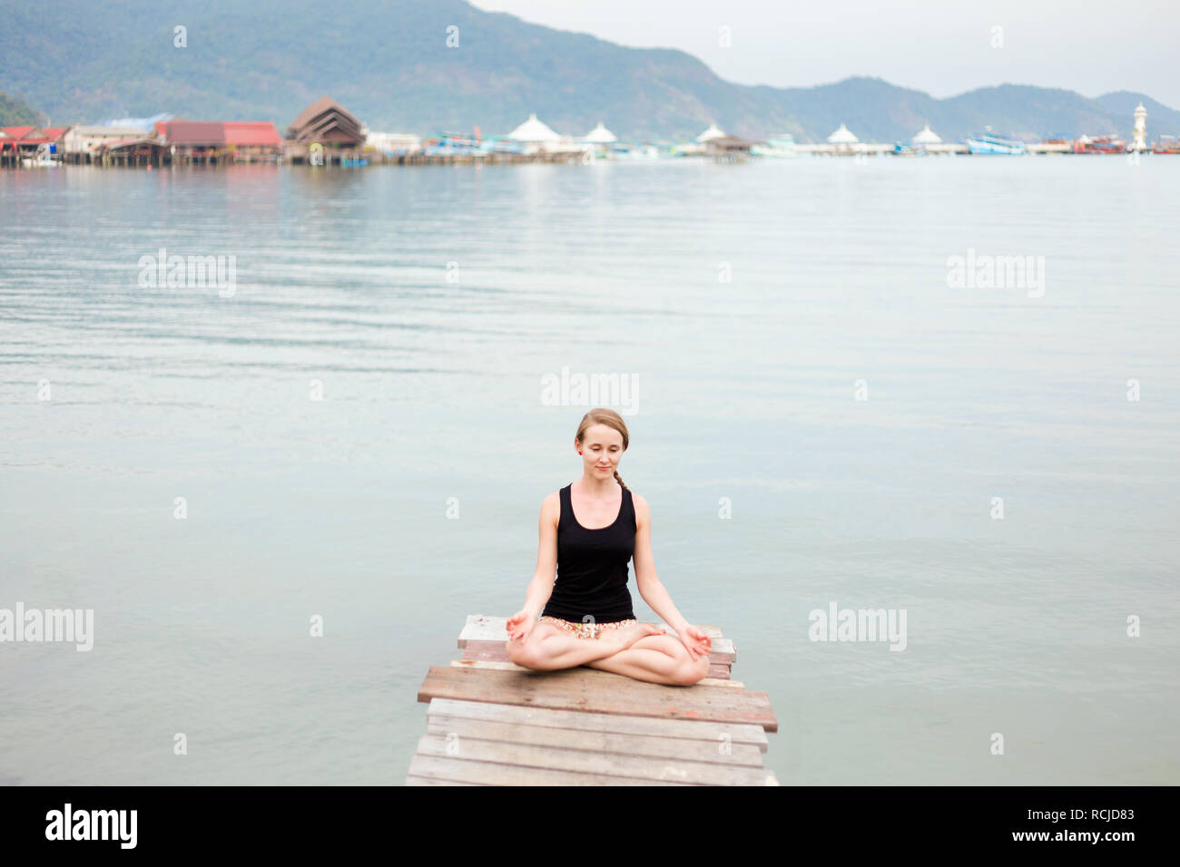 Summer yoga session on a pier - Koh Chang Bang Bao fisherman village, Meditation - lotus pose - padma asana. Activity in south east Asia Stock Photo