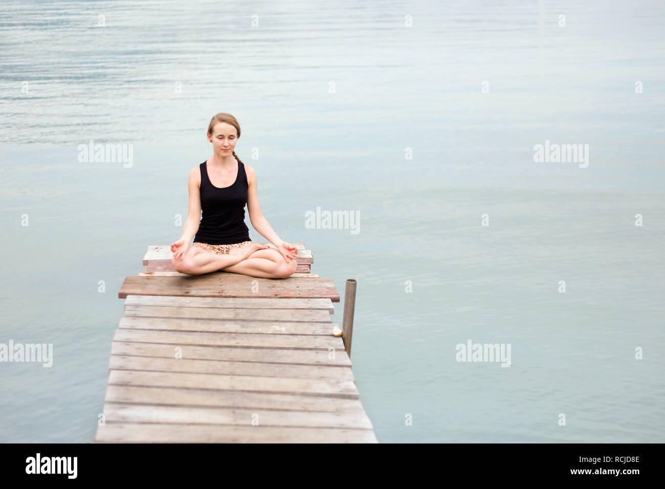 Summer yoga session on a pier - Koh Chang Bang Bao fisherman village, Meditation - lotus pose - padma asana. Activity in south east Asia Stock Photo