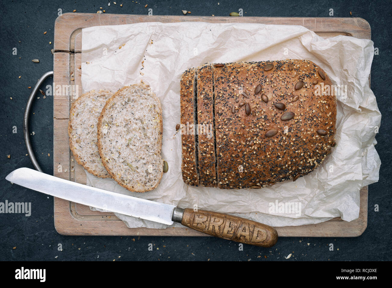 Seeded bread with a vintage bread knife on a bread board. UK Stock Photo