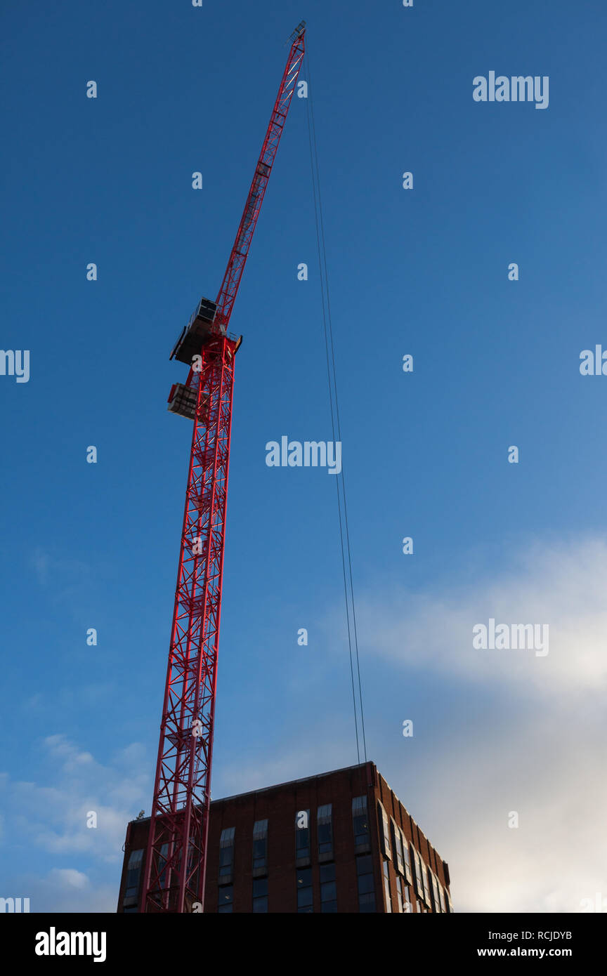 A bright red tower crane reaches high into a blue sky Stock Photo - Alamy