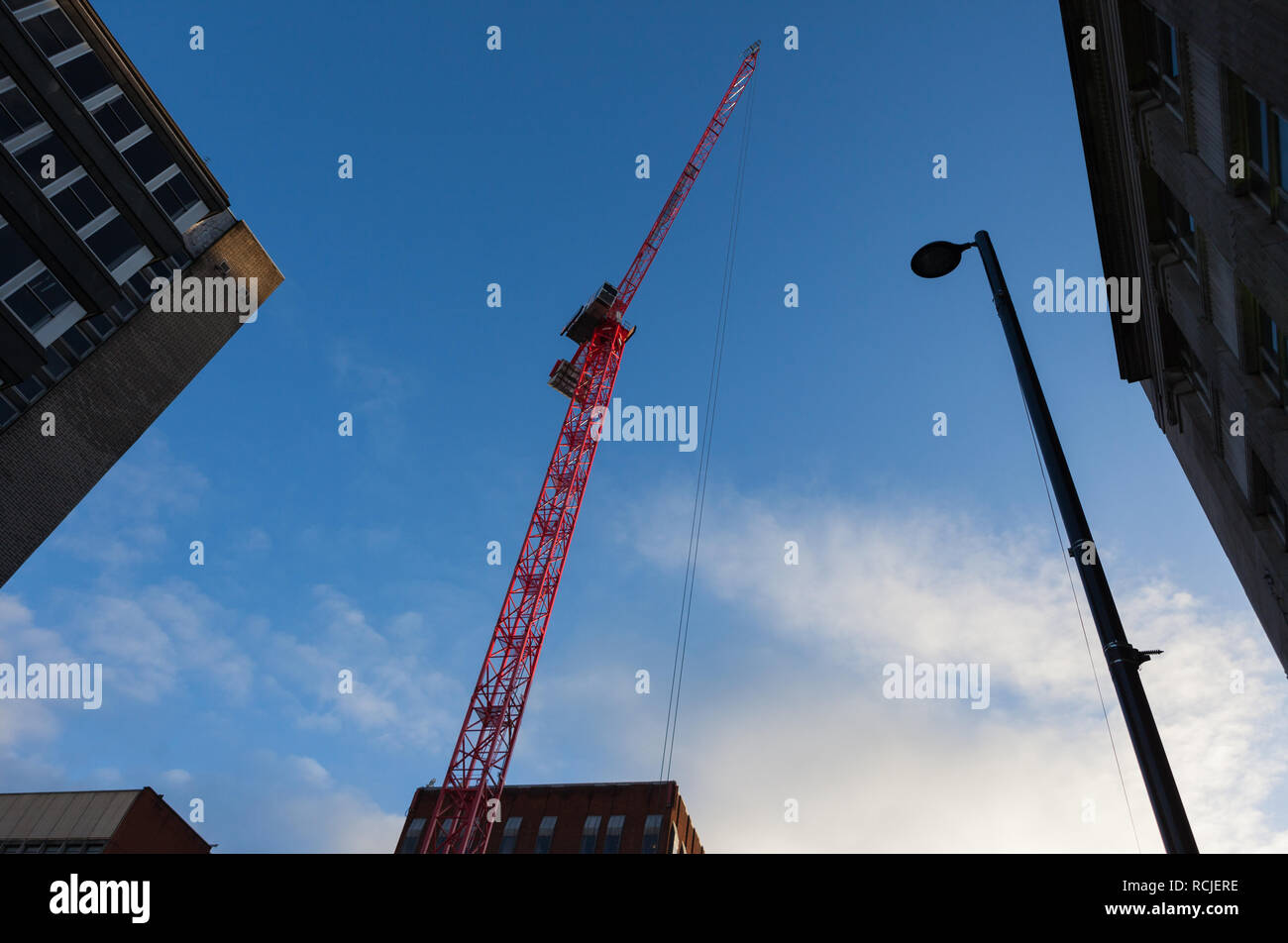 A bright red tower crane reaches high into a blue sky Stock Photo - Alamy