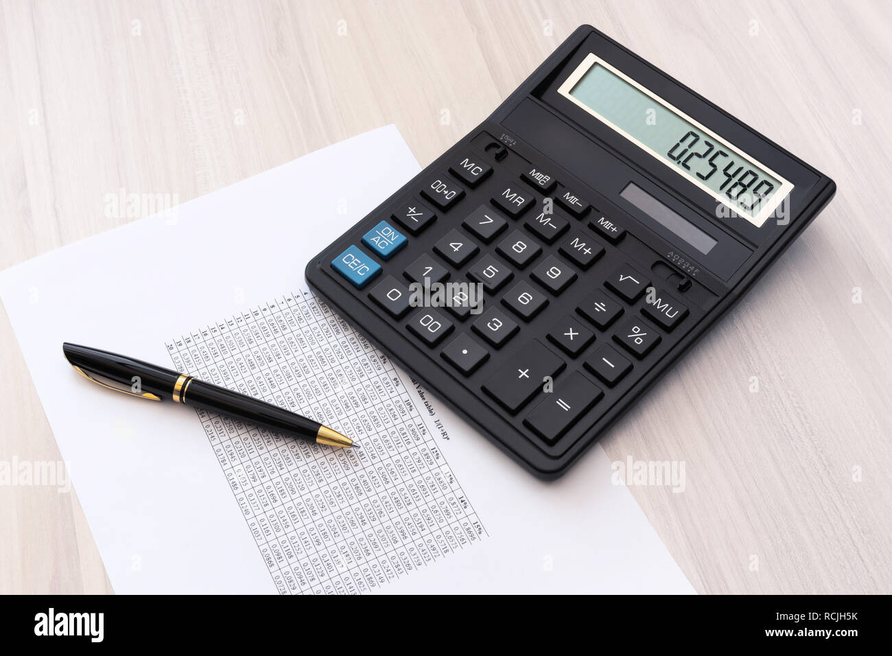 Calculator, pen and sheet of paper with spreadsheet  on the table Stock Photo