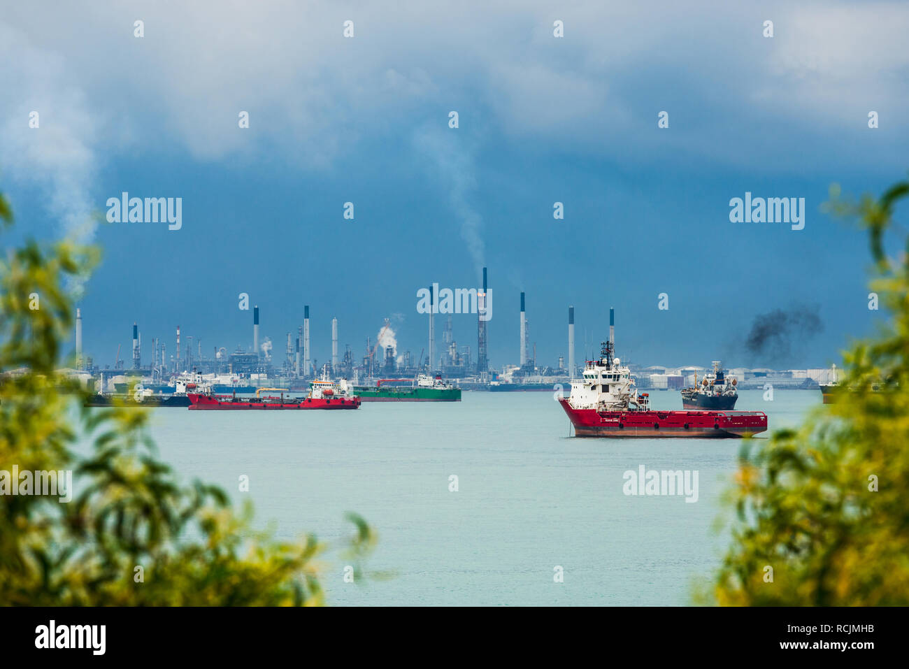 View of the Singapore Strait from Sentosa Island. Ships, industrial landscape and stormy weather. Stock Photo
