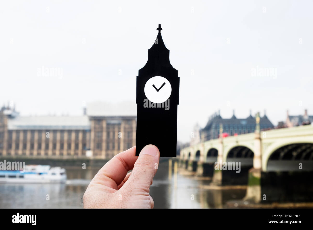 closeup of the hand holding a paper cutout in the shape of the Clock Tower of the Palace of Westminster in London, United Kingdom Stock Photo