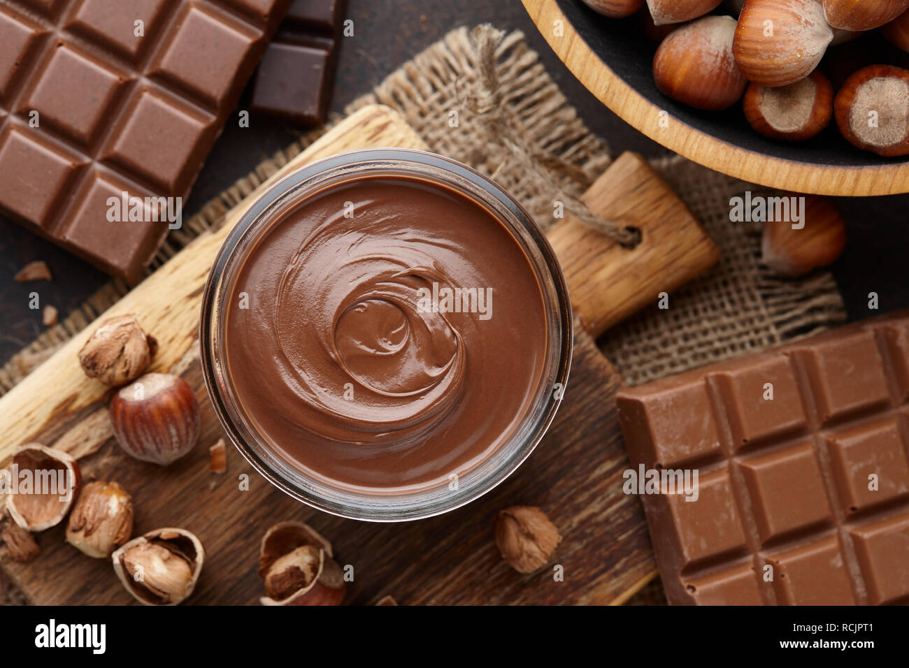Chocolate spread, nuts and chocolate bars on table Stock Photo