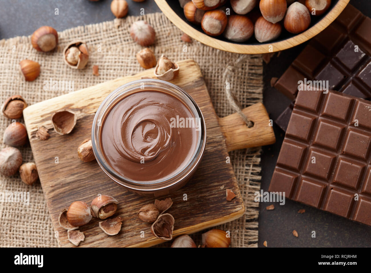 Chocolate spread, nuts and chocolate bars on table Stock Photo