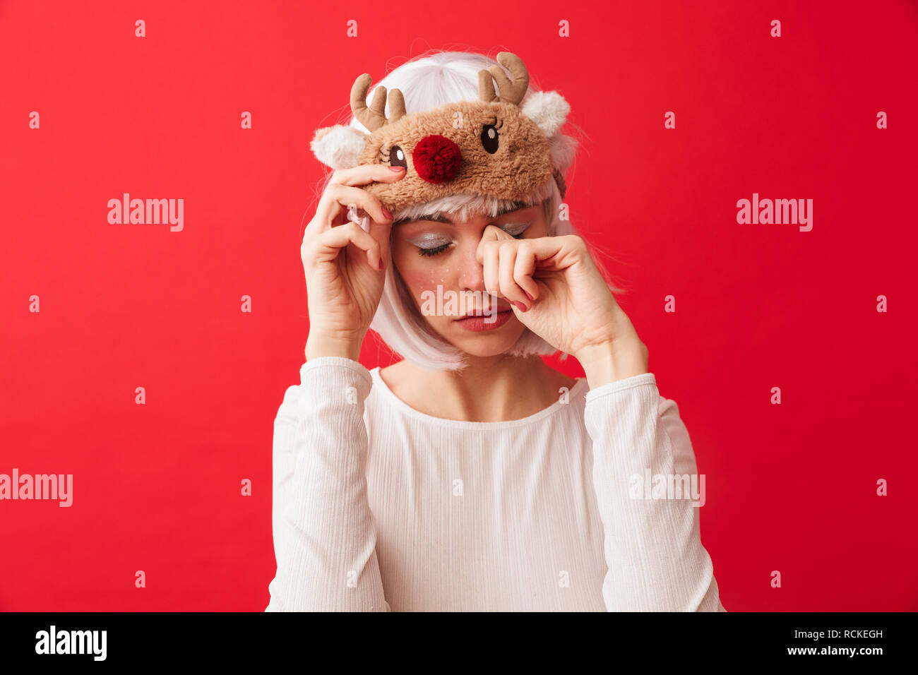 Image of a tired young woman dressed in carnival christmas costume posing isolated over red wall background. Stock Photo