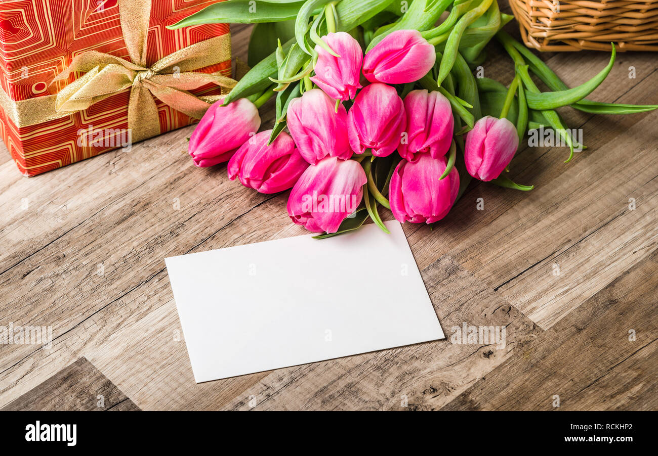 Beautiful bouquet from pink tulips and a gift on a table Stock Photo
