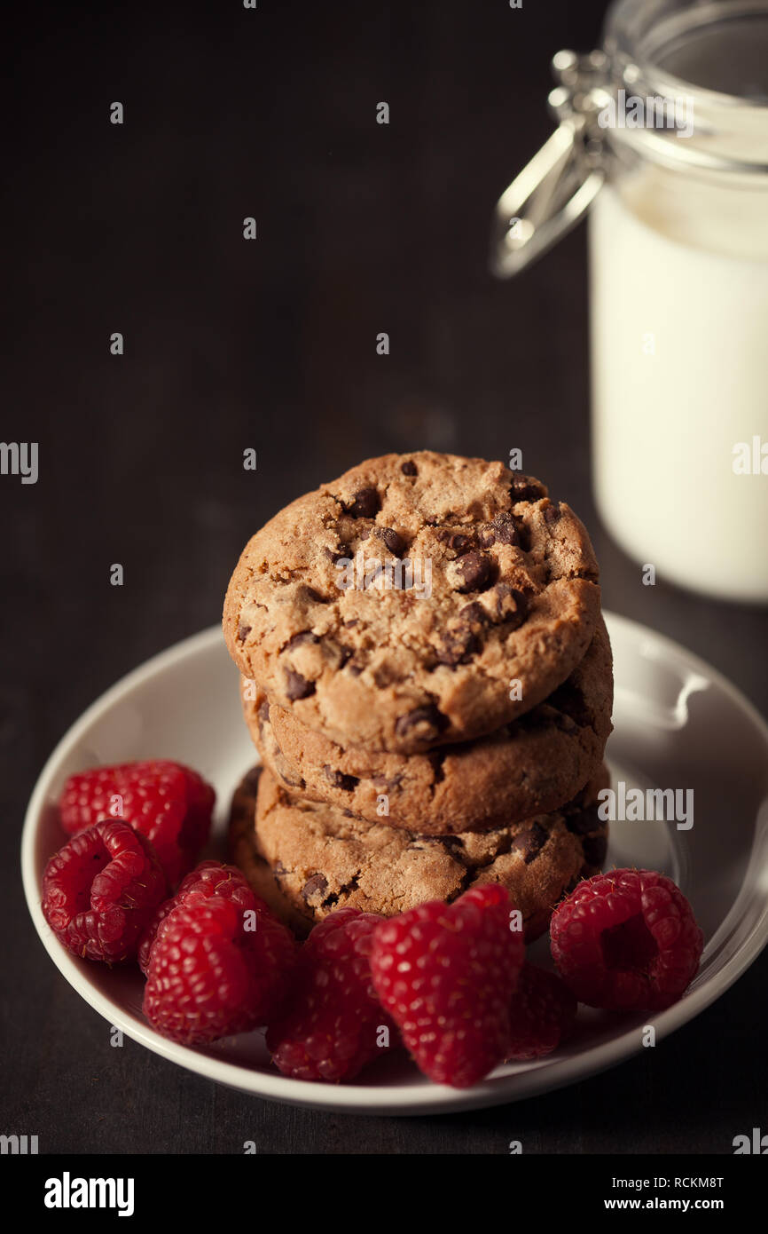 Chocolate chip cookies with red raspberry and milk on rustic wood ...