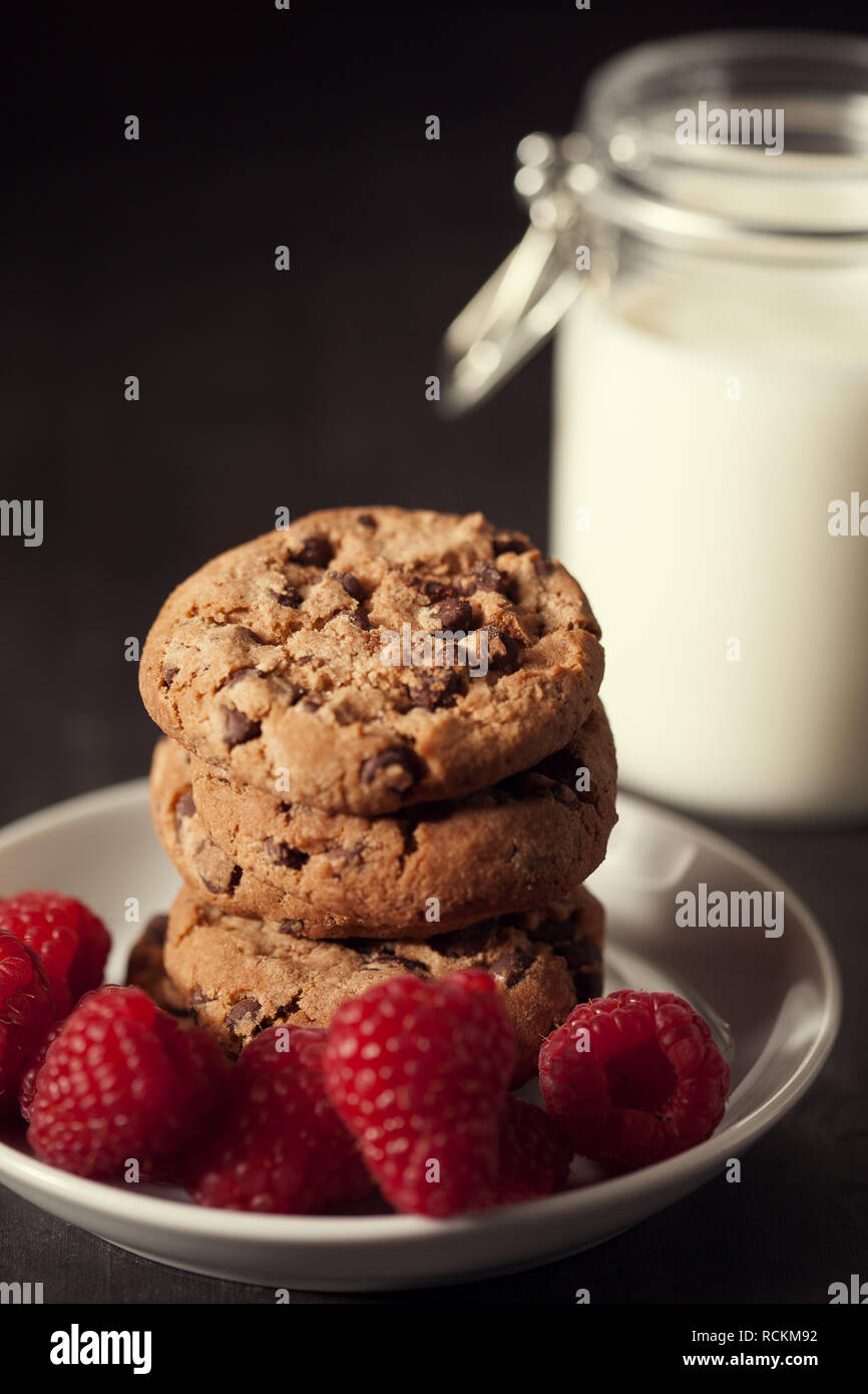 Chocolate chip cookies with red raspberry and milk on rustic wood ...
