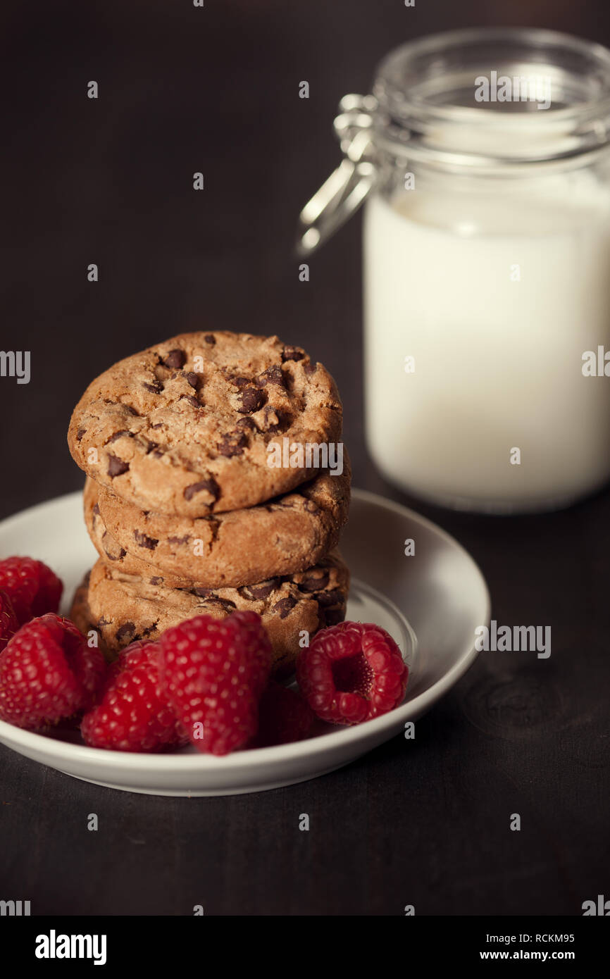 Chocolate chip cookies with red raspberry and milk on rustic wood ...