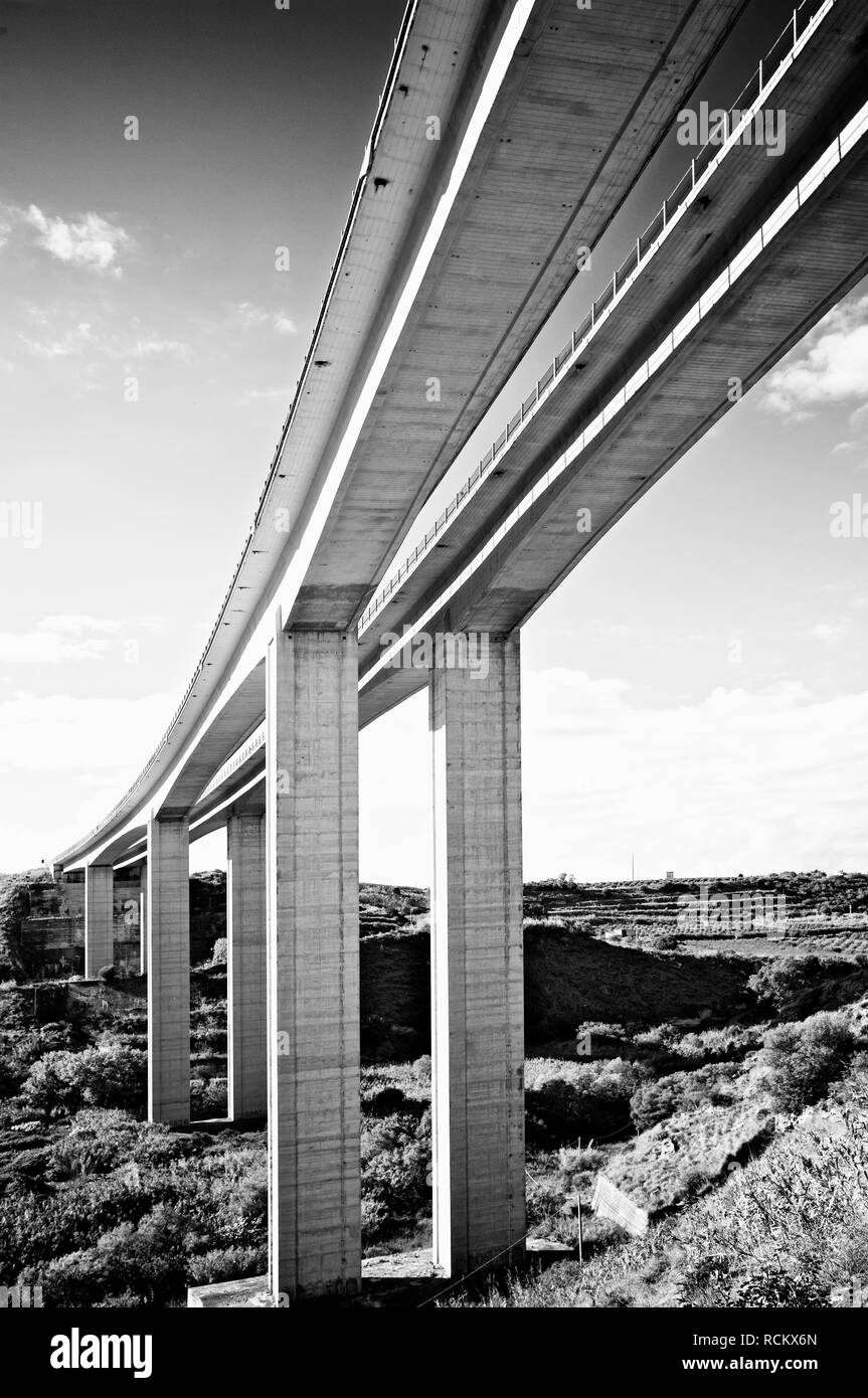 View from underneath large scale road bridge in daytime, black and white Stock Photo