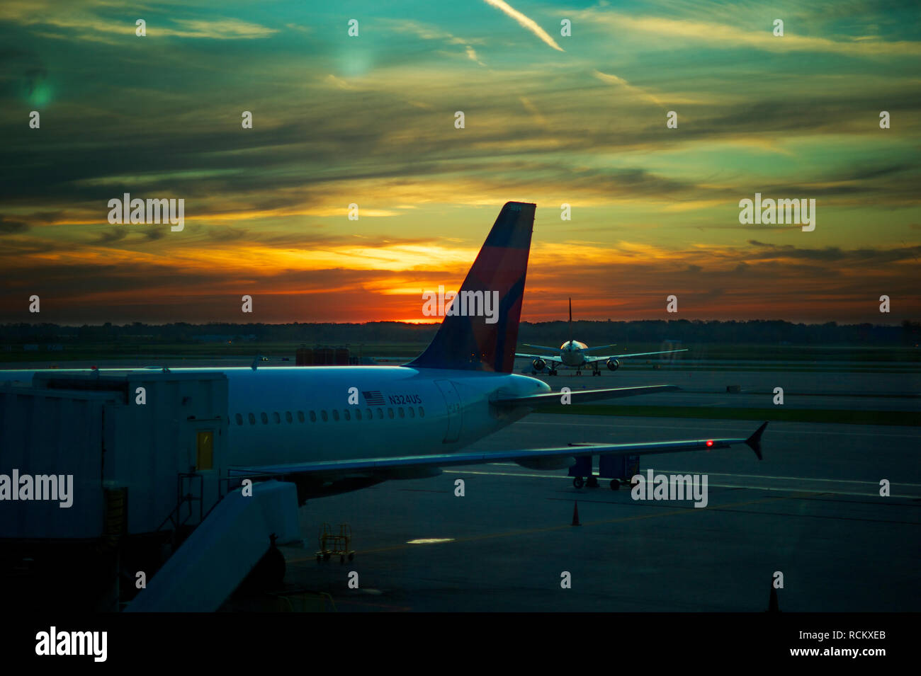 Stationary aeroplanes on runway underneath dramatic sunset Stock Photo