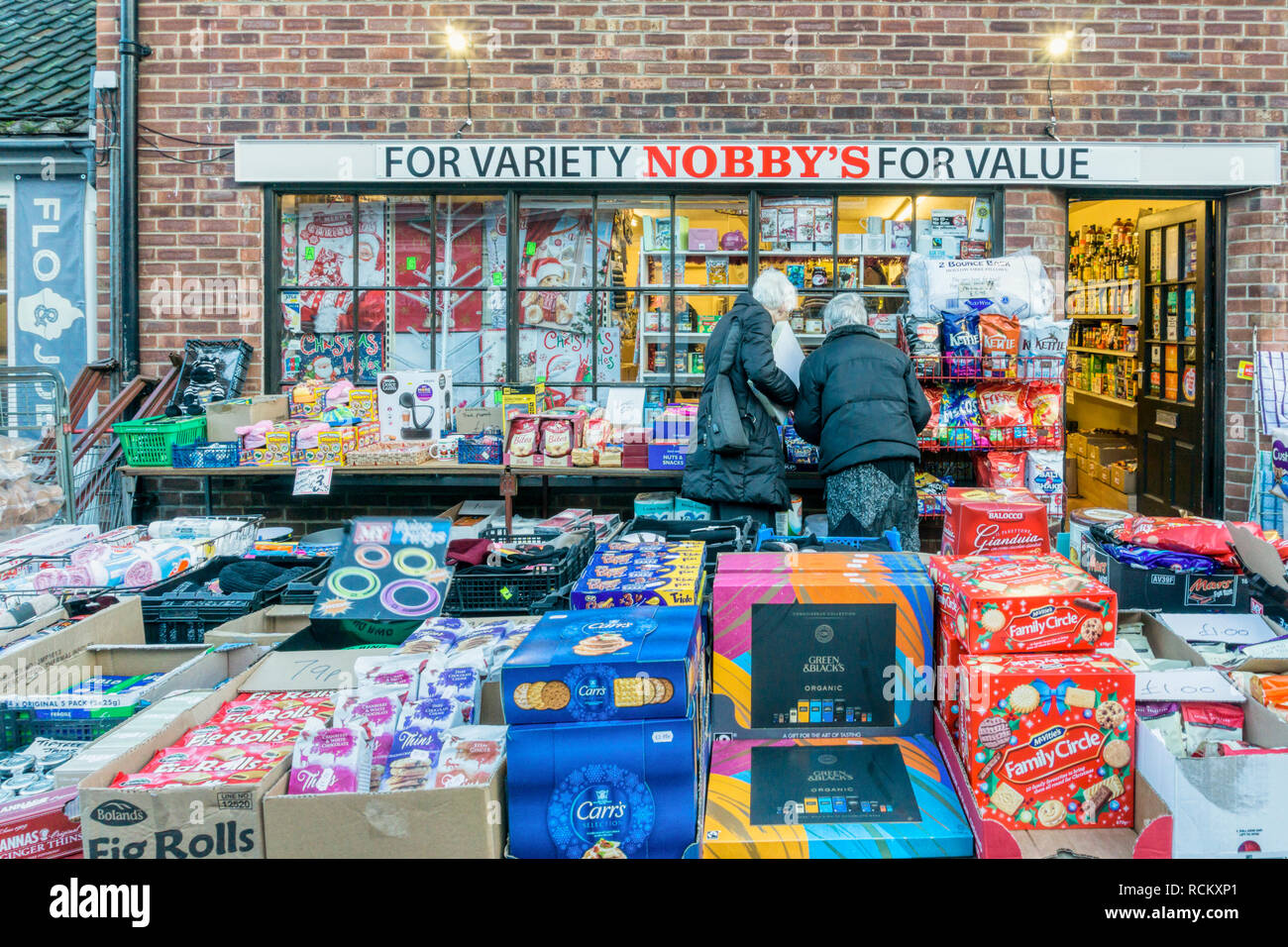 Two shoppers browse items for sale on tables outside Nobby's general shop in Wells-next-the-Sea, Norfolk. Stock Photo