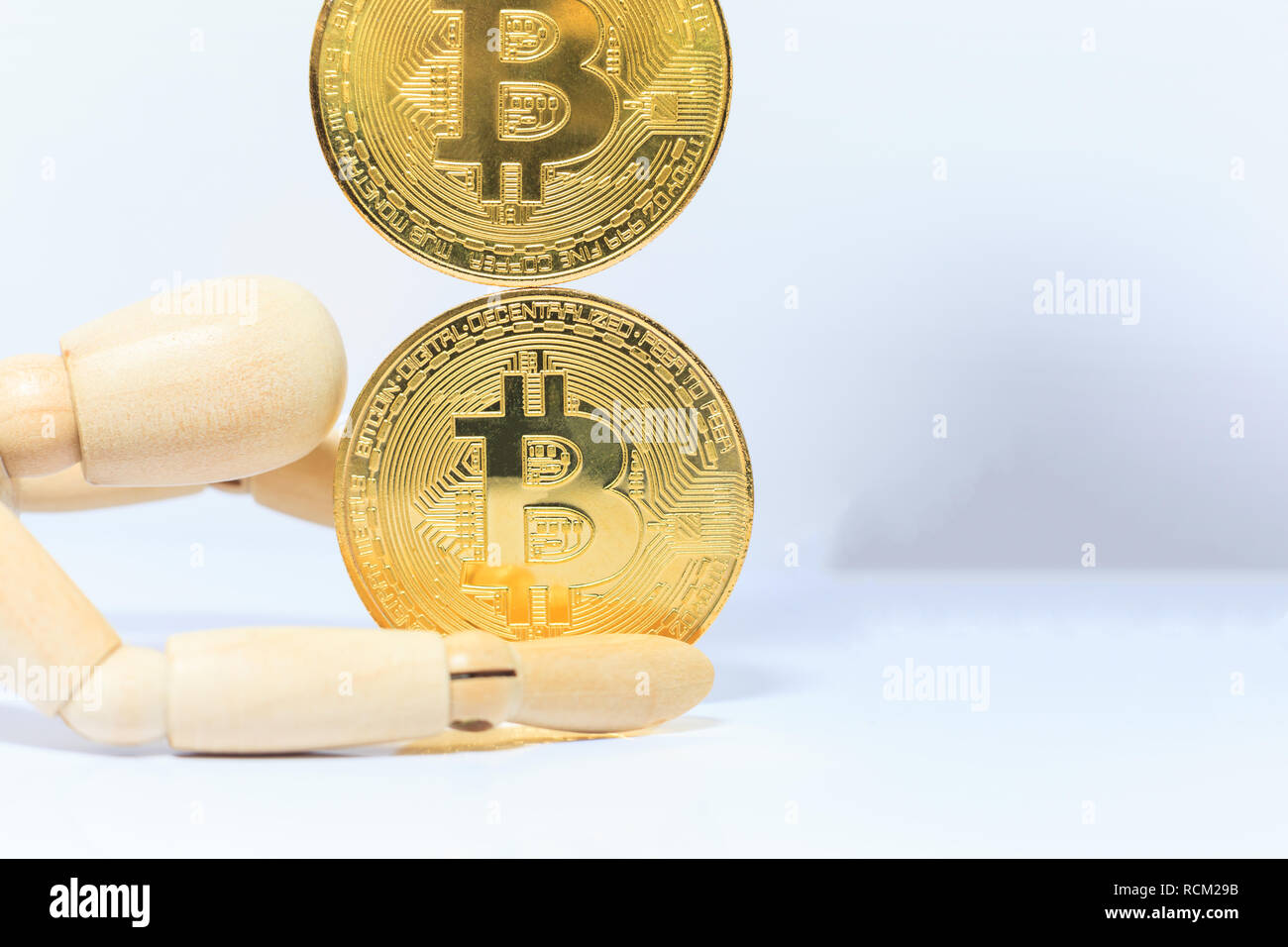 wooden robot model stops falling Bitcoin cryptocurrency token on white ...
