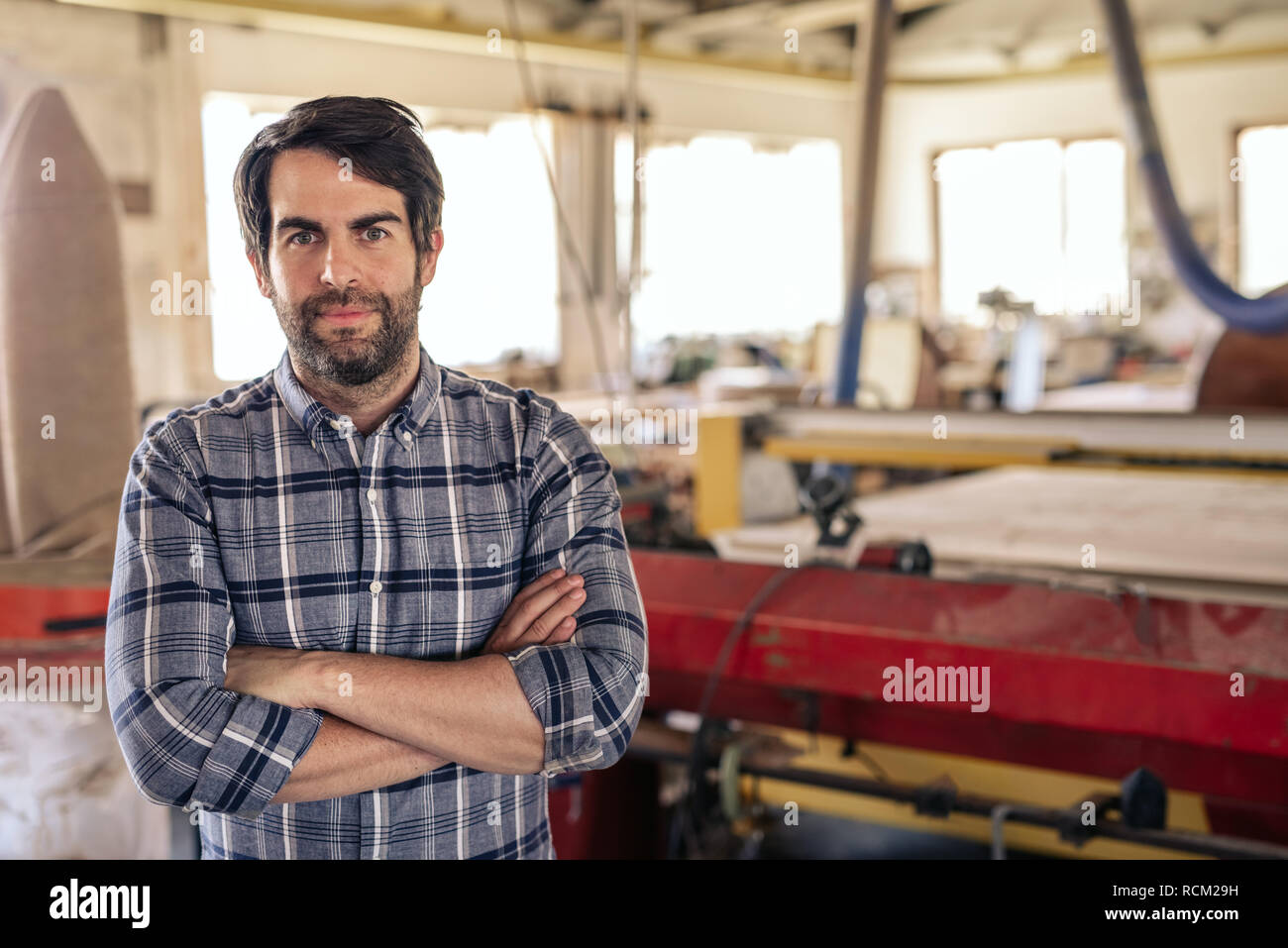 Carpenter standing with his arms crossed in woodworking shop Stock Photo