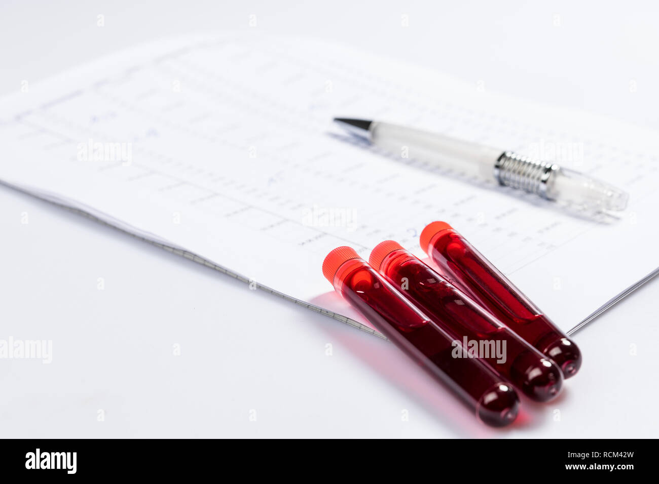 Test tubes with blood on white table with test chart and ballpoint pen Stock Photo