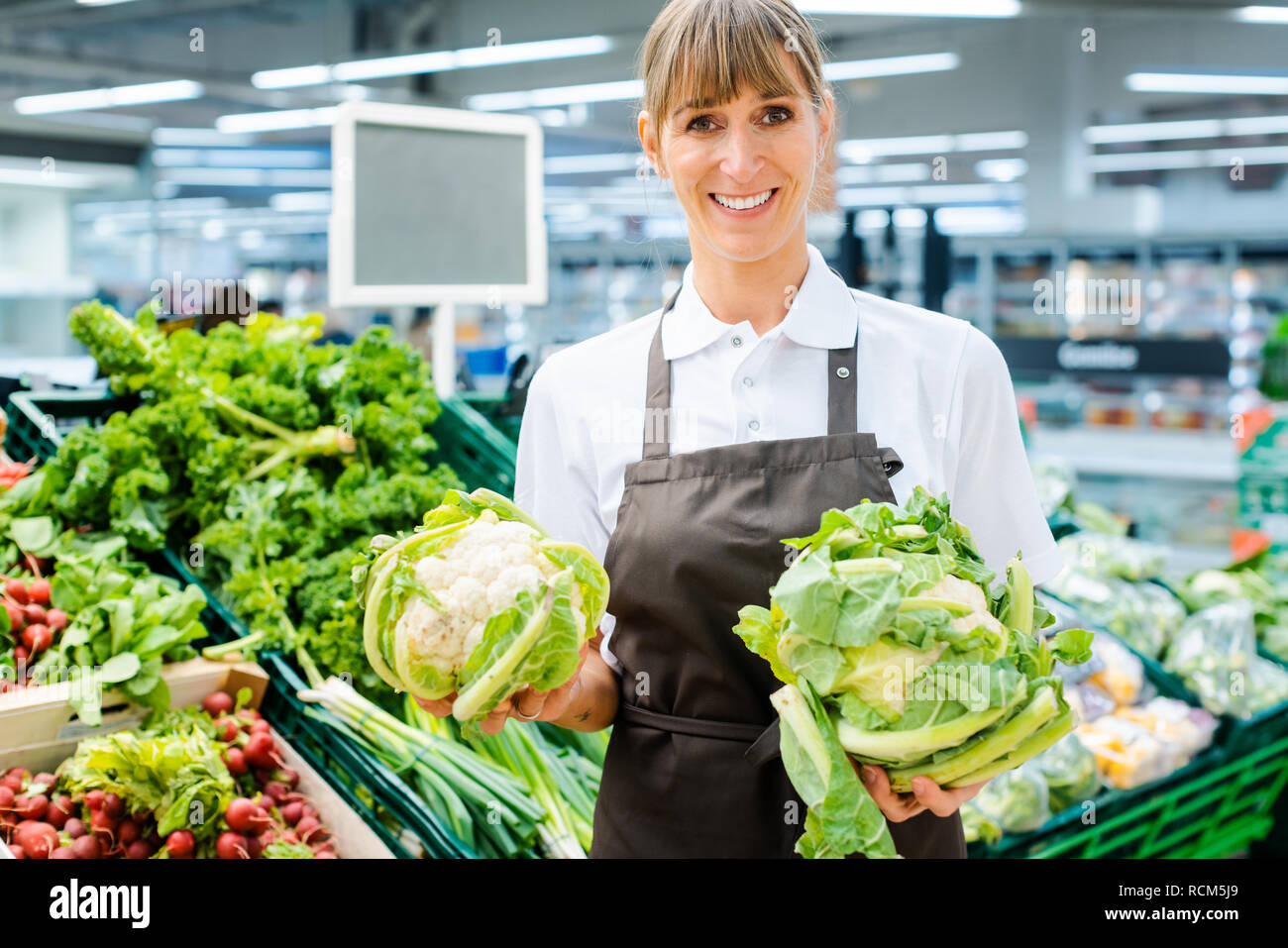Shop Assistant Woman In Supermarket Showing The Fresh Produce Stock shop-assistant-woman-in-supermarket-showing-the-fresh-produce-stock