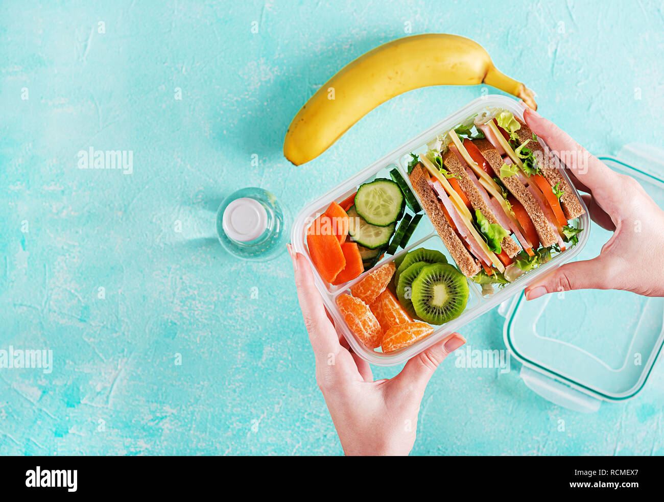 Lunchbox in hands. School lunch box with sandwich, vegetables, water
