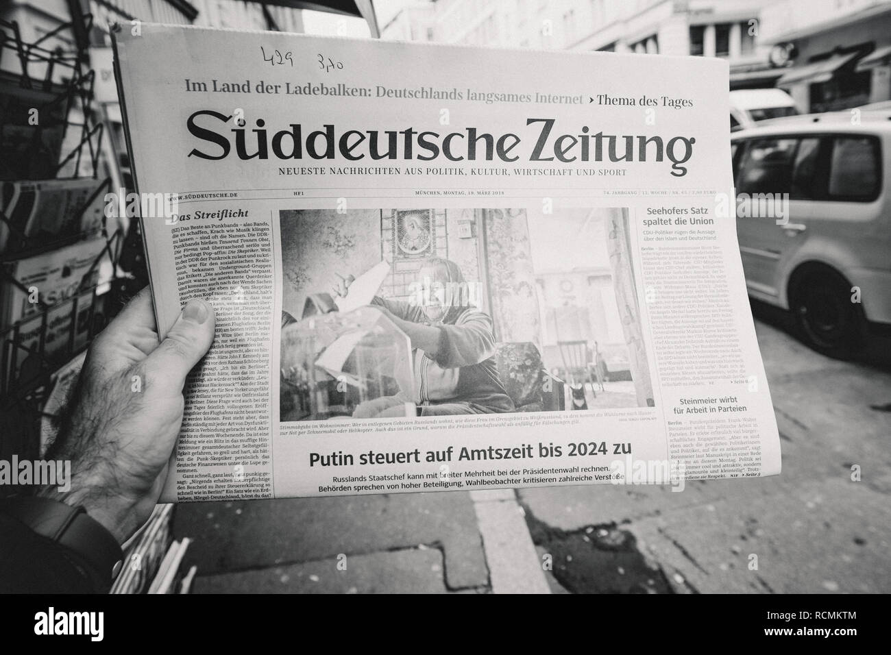 PARIS, FRANCE - MAR 19, 2017: Man reading buying German Sudeutsche Zeitung newspaper at press kiosk featuring Russian presidential election from 2018 and situation in the country with senior woman black and white,  Stock Photo