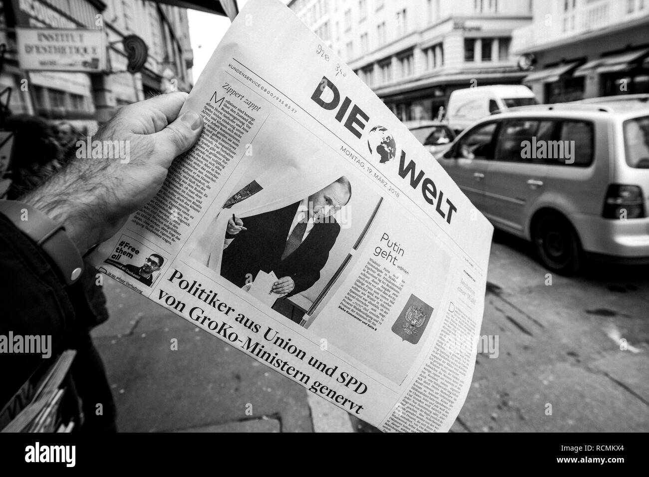 PARIS, FRANCE - MAR 19, 2017: Man reading buying German Die Welt newspaper at press kiosk featuring Russian presidential election from 2018 with the winner Vladimir Putin city background  Stock Photo