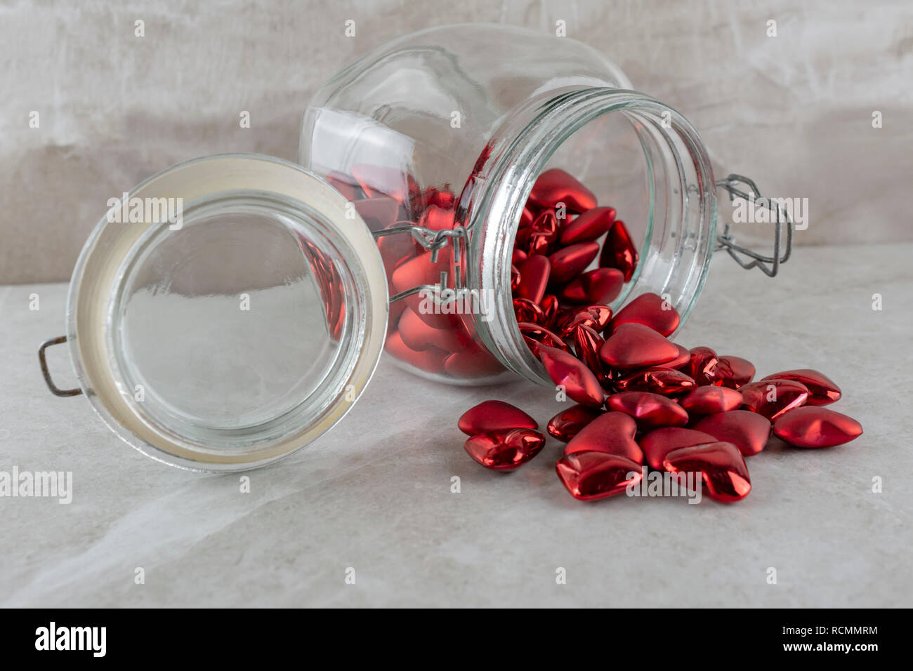 Jar of Red Hearts on side.  Side view.  Tan background. Stock Photo