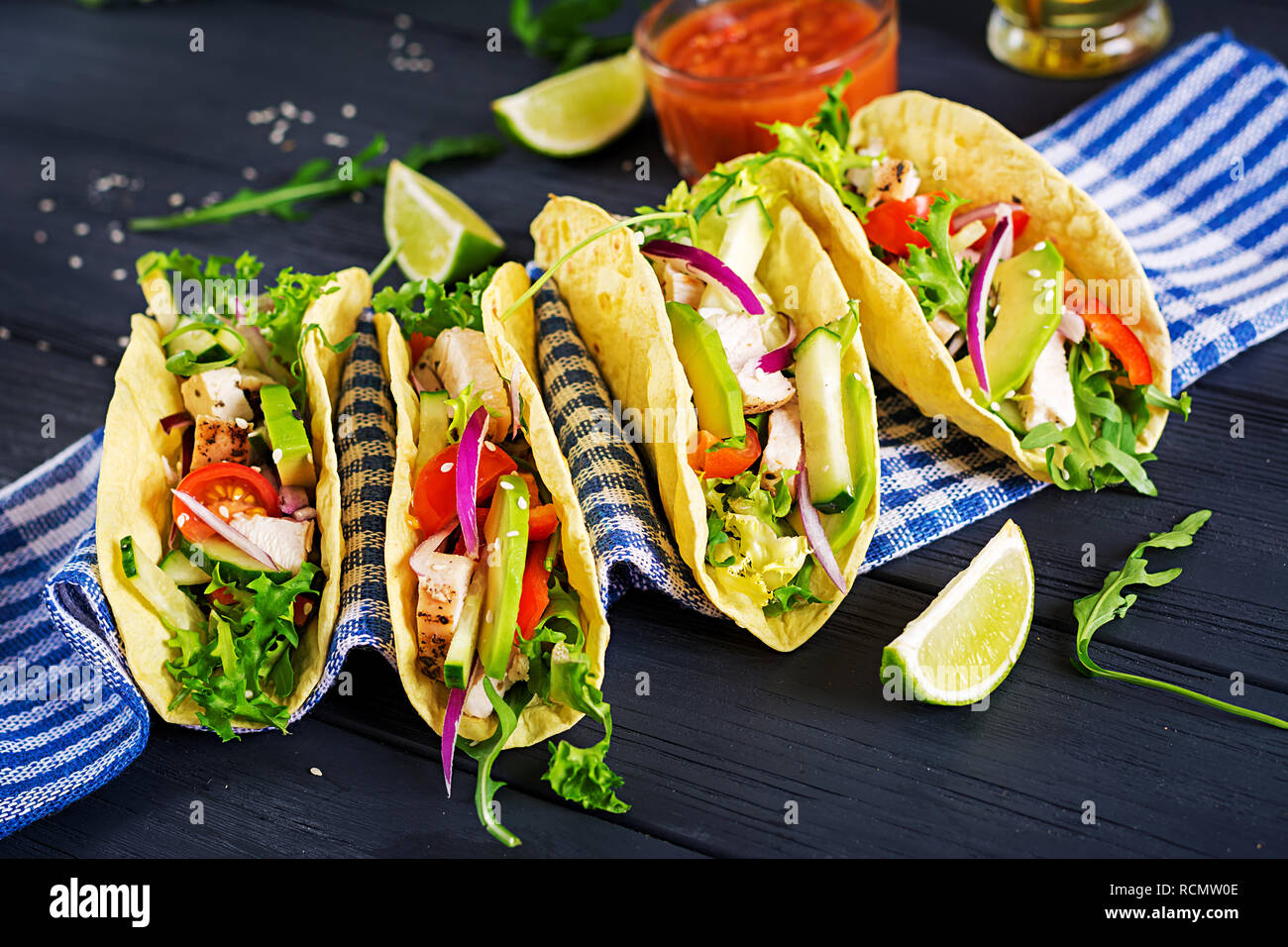 Mexican tacos with chicken meat, avocado, tomato, cucumber and red