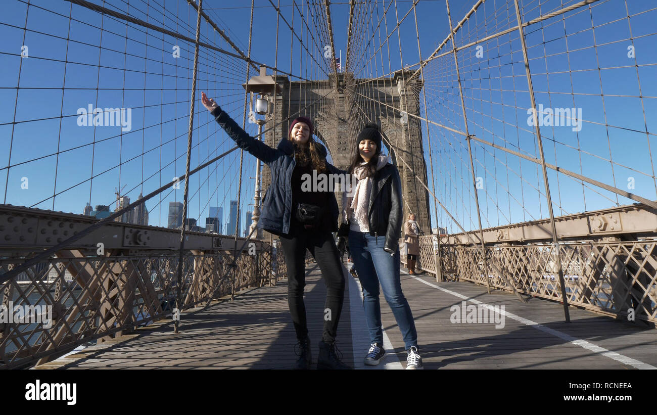 Two girls walk over the famous Brooklyn Bridge in New York Stock Photo