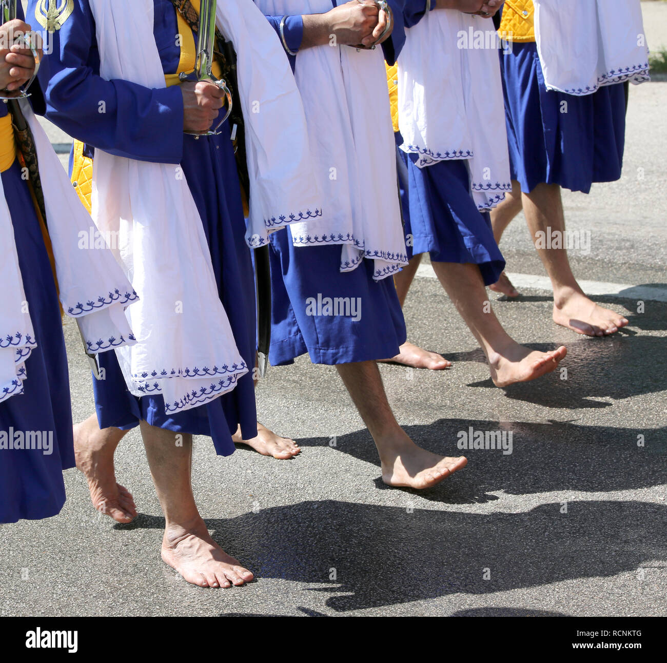 Sikh men dressed in a traditional blue dress walk barefoot along the road  during a religious rally Stock Photo - Alamy