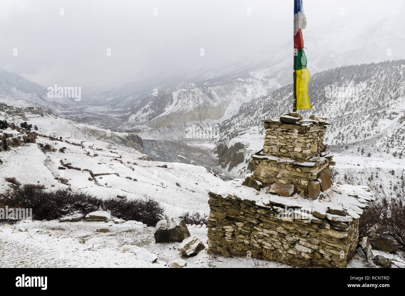 Chorten and Tibetan prayer flag in snow covered Manang, Annapurna Circuit, Nepal Stock Photo
