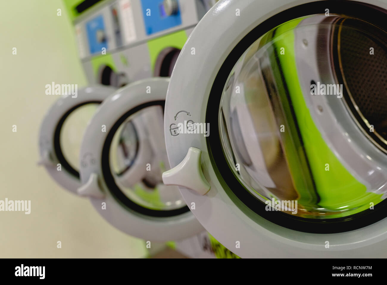 Open doors of industrial washing machines in a public laundry, door