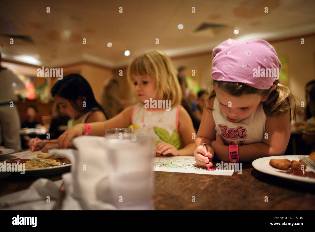 Three young girls coloring in at a table in a child friendly restaurant. Stock Photo