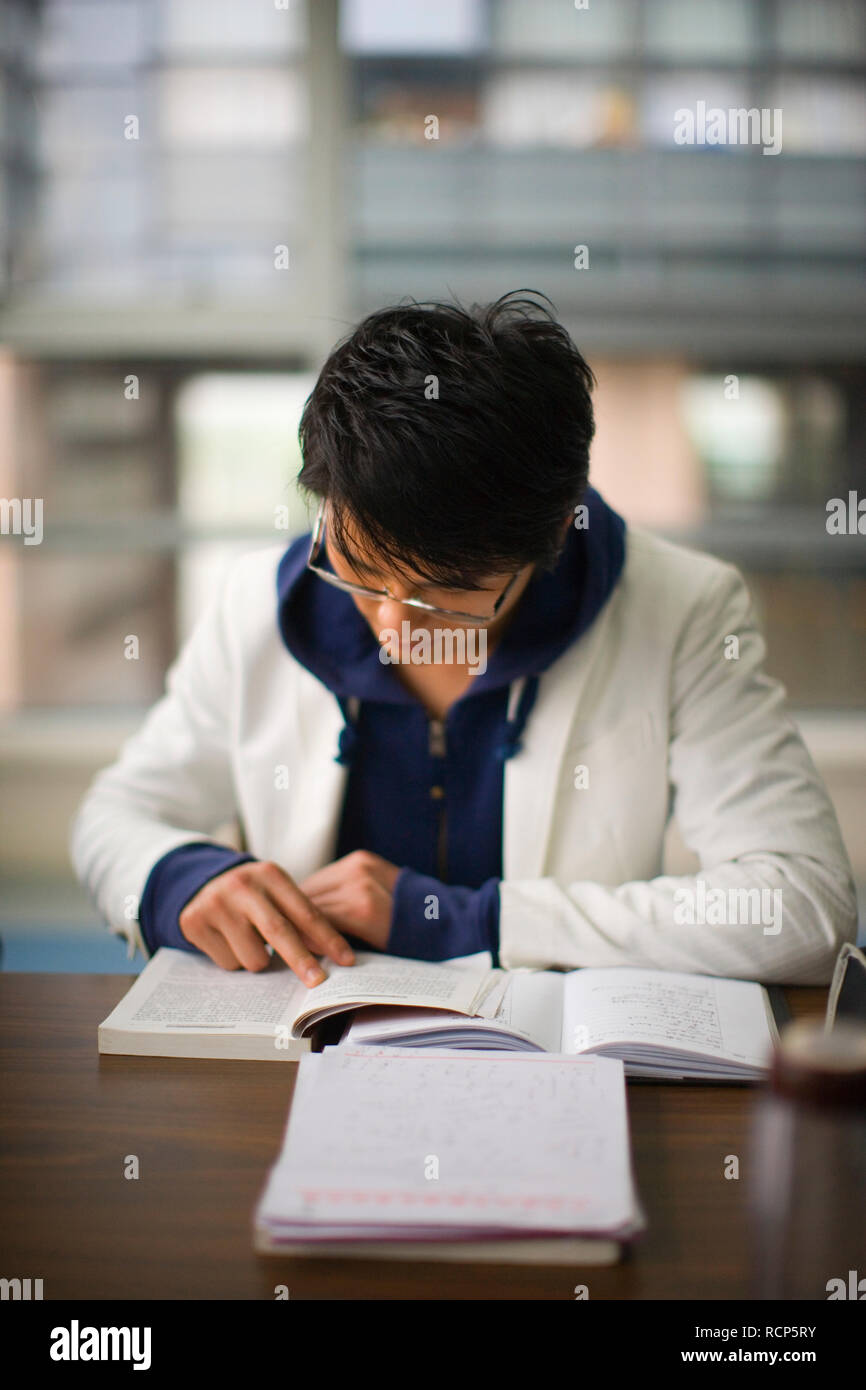 Teenage boy reading in a classroom Stock Photo - Alamy