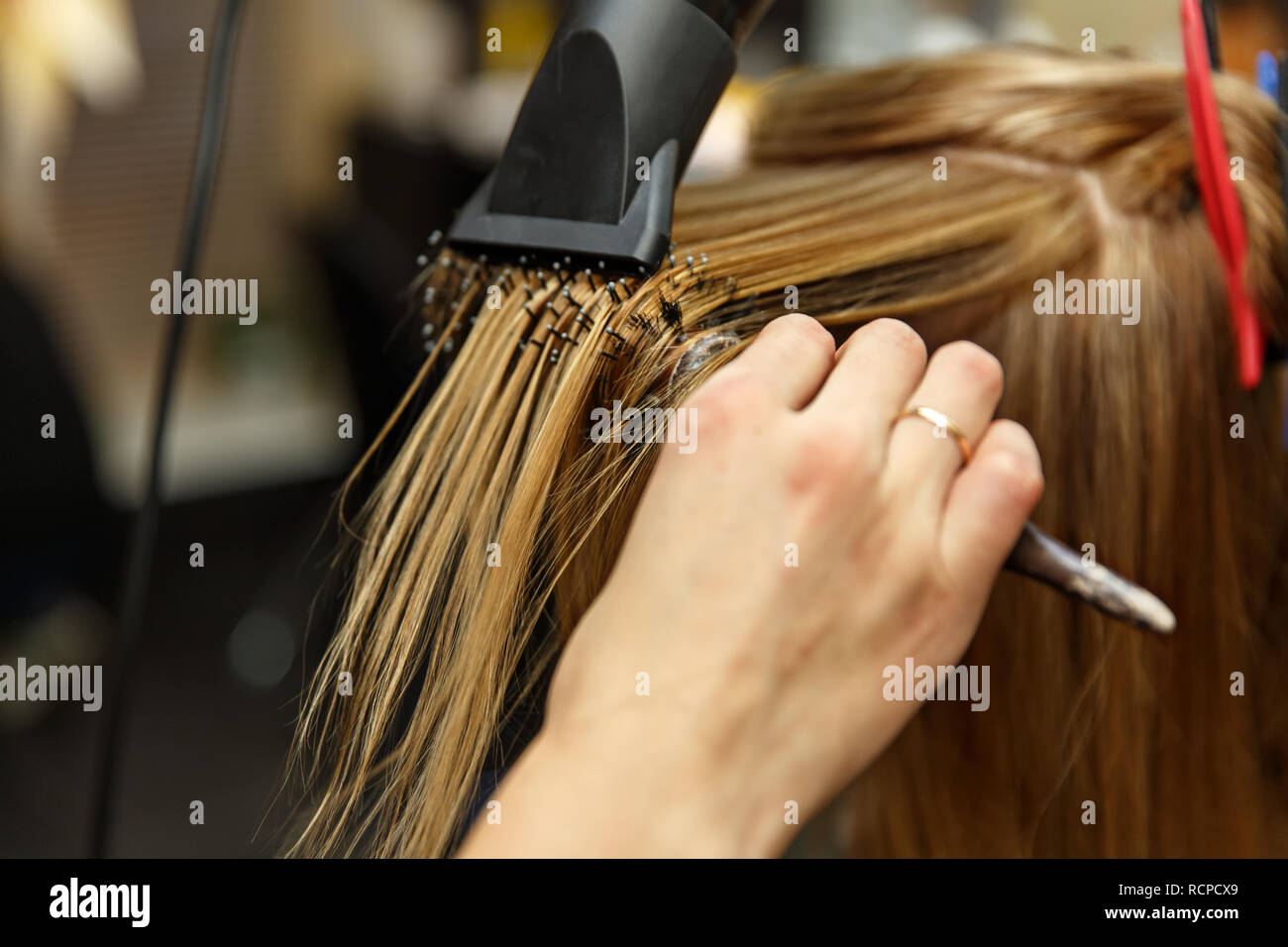 Professional hairdresser dyeing hair of her client in salon. Haircutter