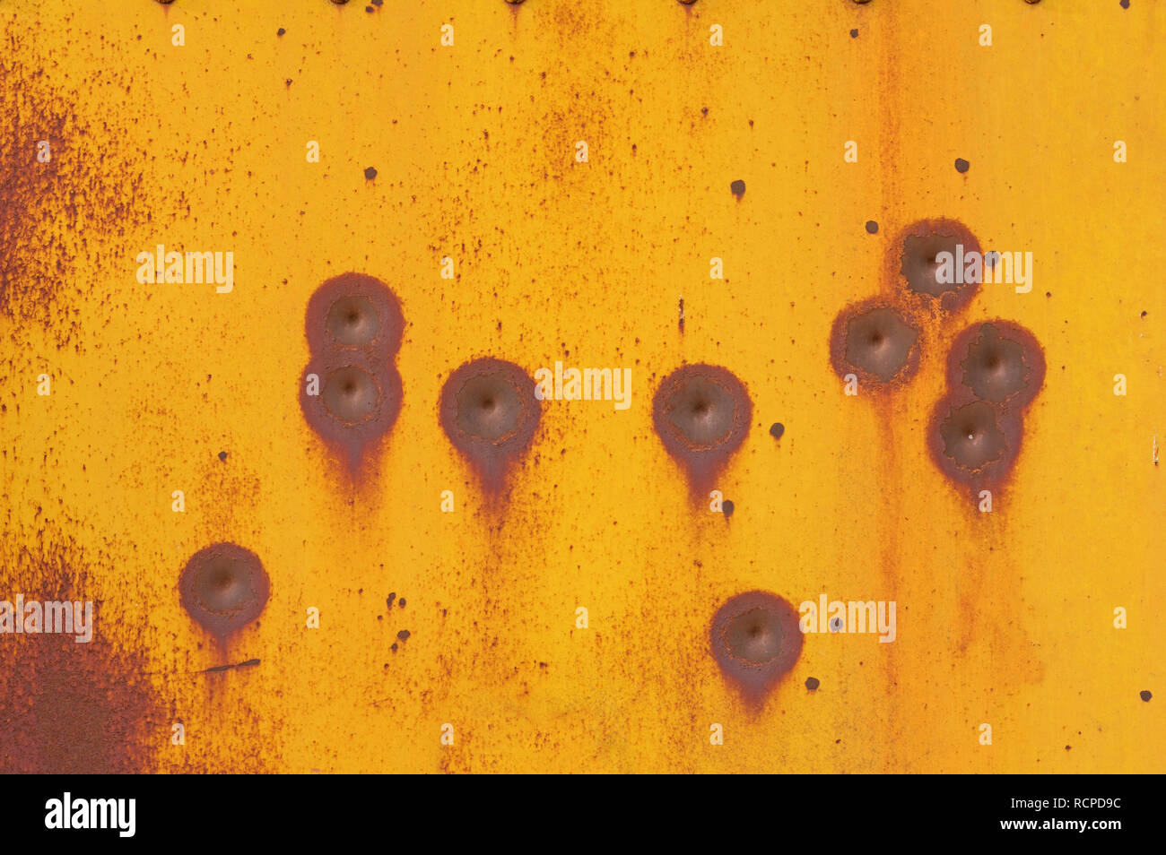 damaged old yellow painted steel metal surface with rust and bullet marks Stock Photo