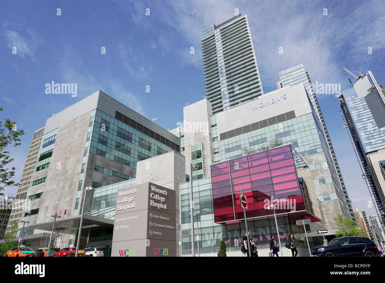 Toronto Women's Collage Hospital building with front entrance, taxi, cars, and people under blue sky and white clouds Stock Photo