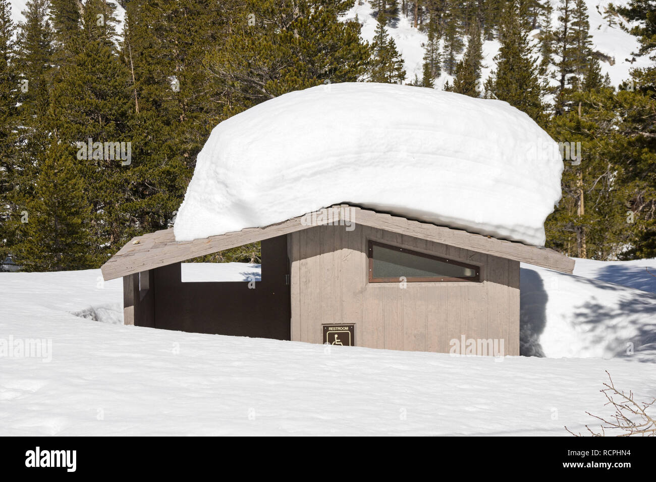 forest service concrete outhouse restroom half covered in deep winter snow Stock Photo