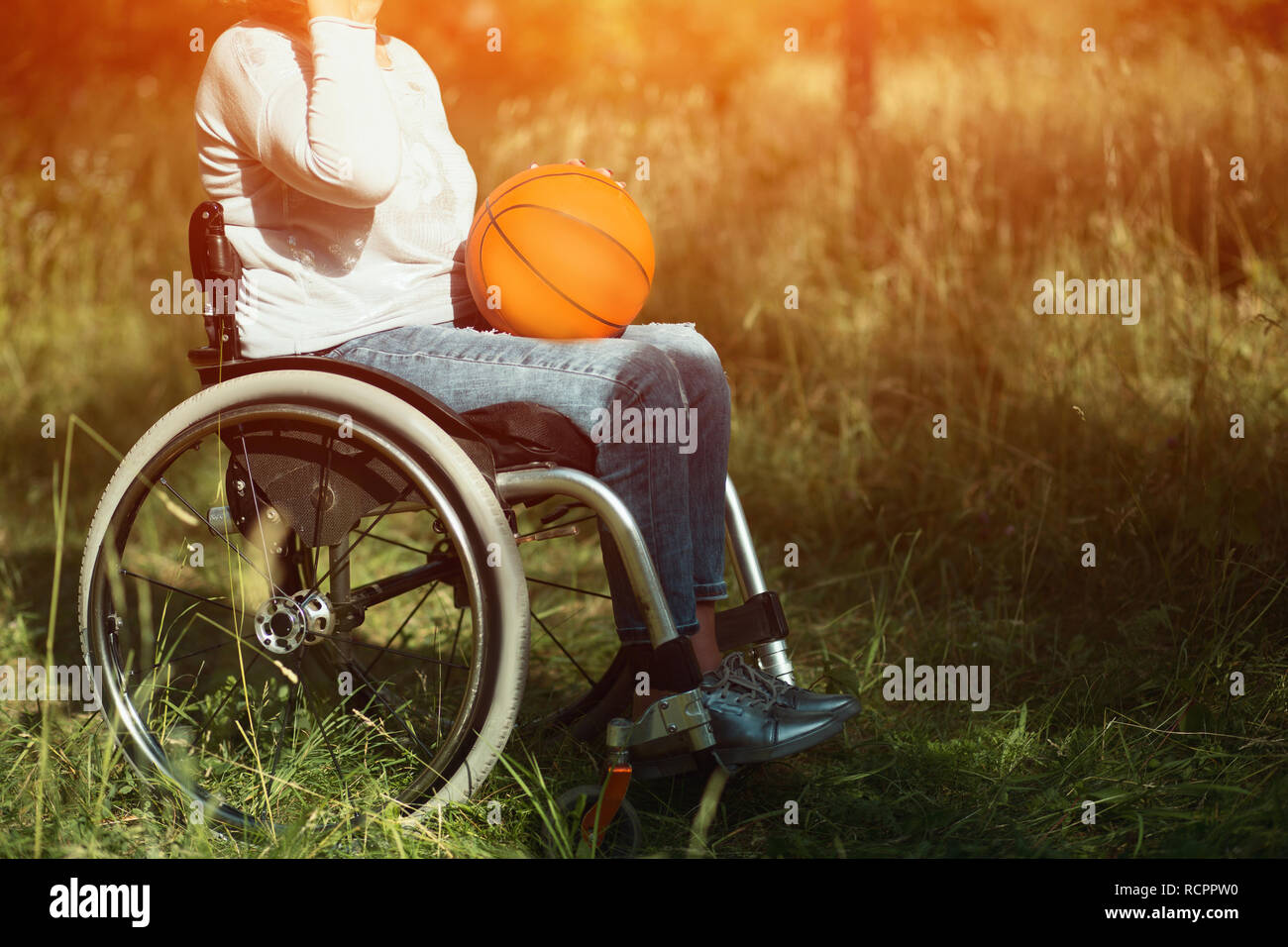 Woman in wheelchair with basket ball on her laps Stock Photo