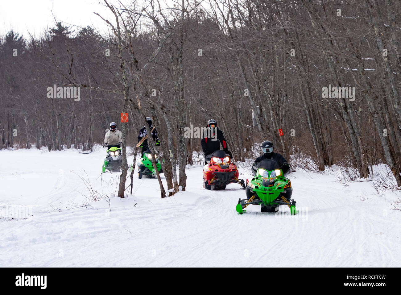 Four snowmobiles riding on a groomed trail along the Sacandaga River