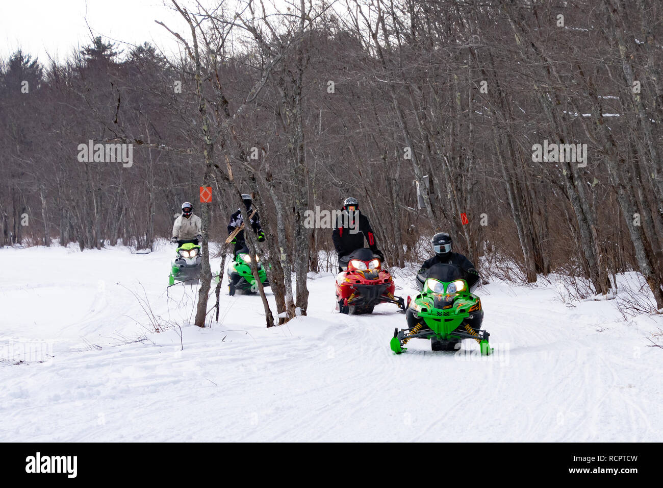 Four snowmobiles riding on a groomed trail along the Sacandaga River Valley near Speculator, NY USA Stock Photo