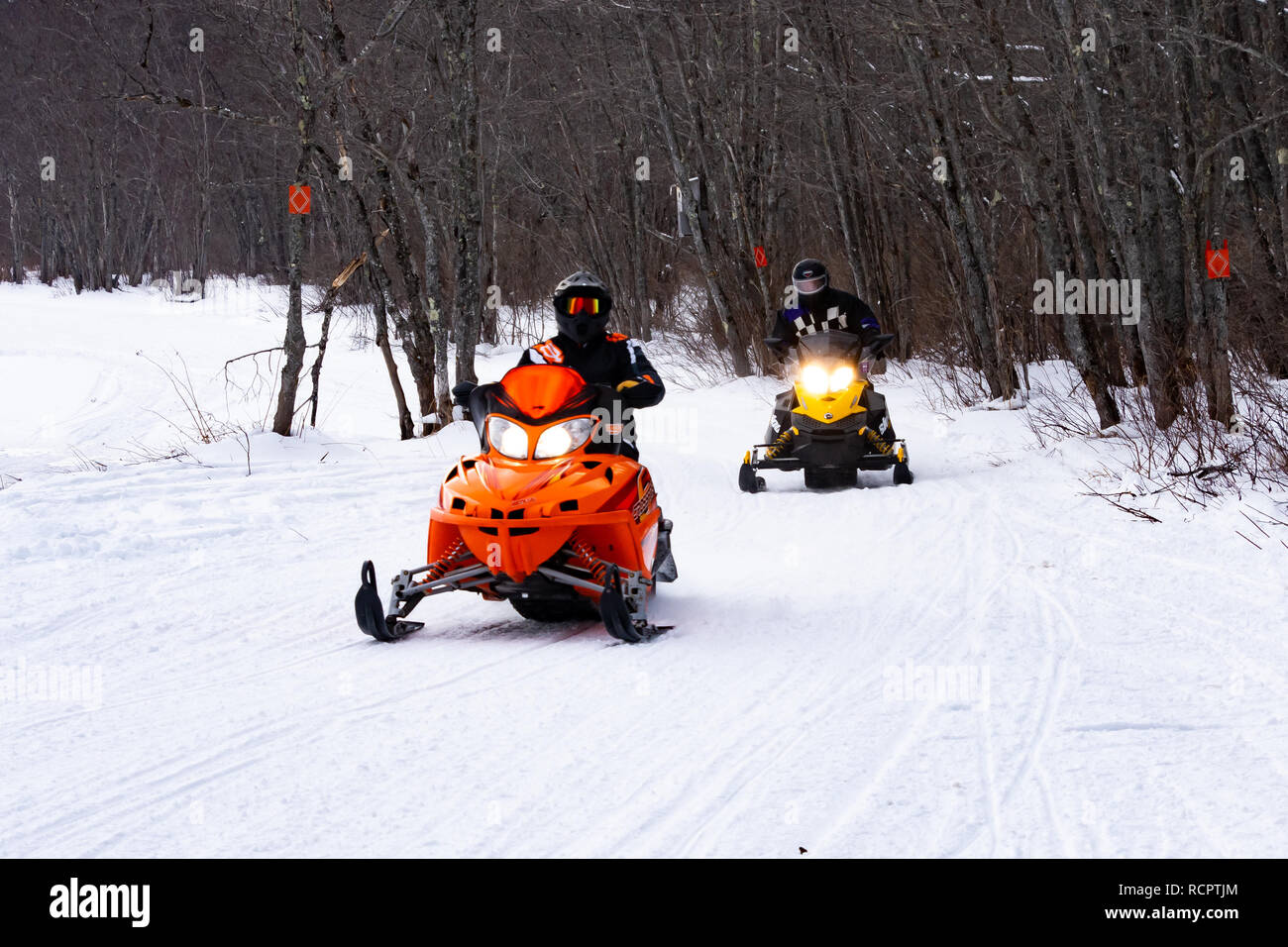 snowmobiles riding on a groomed trail along the Sacandaga River Valley near Speculator, NY USA Stock Photo