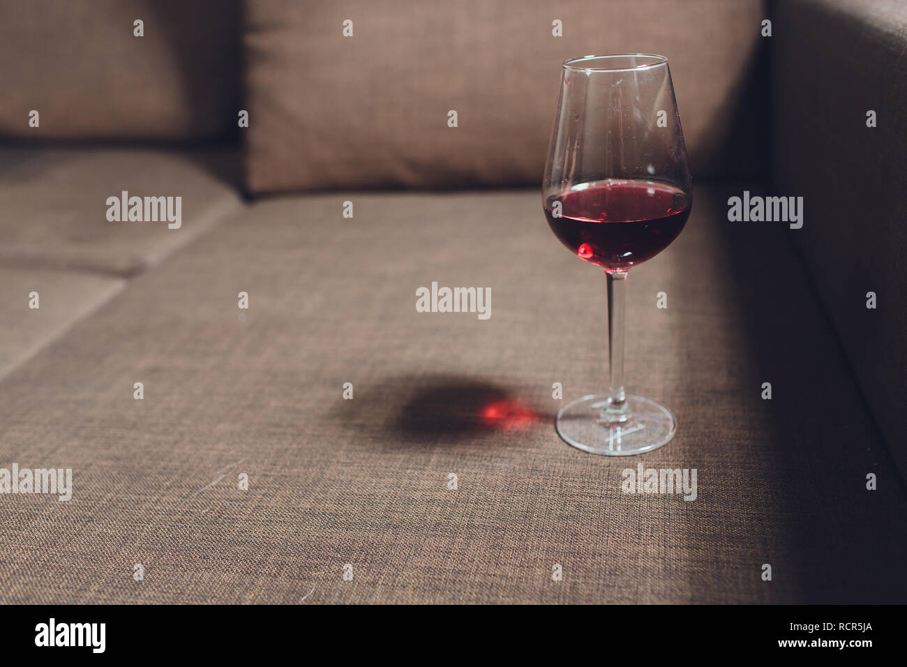 Red wine spilled on a grey couch sofa Stock Photo - Alamy