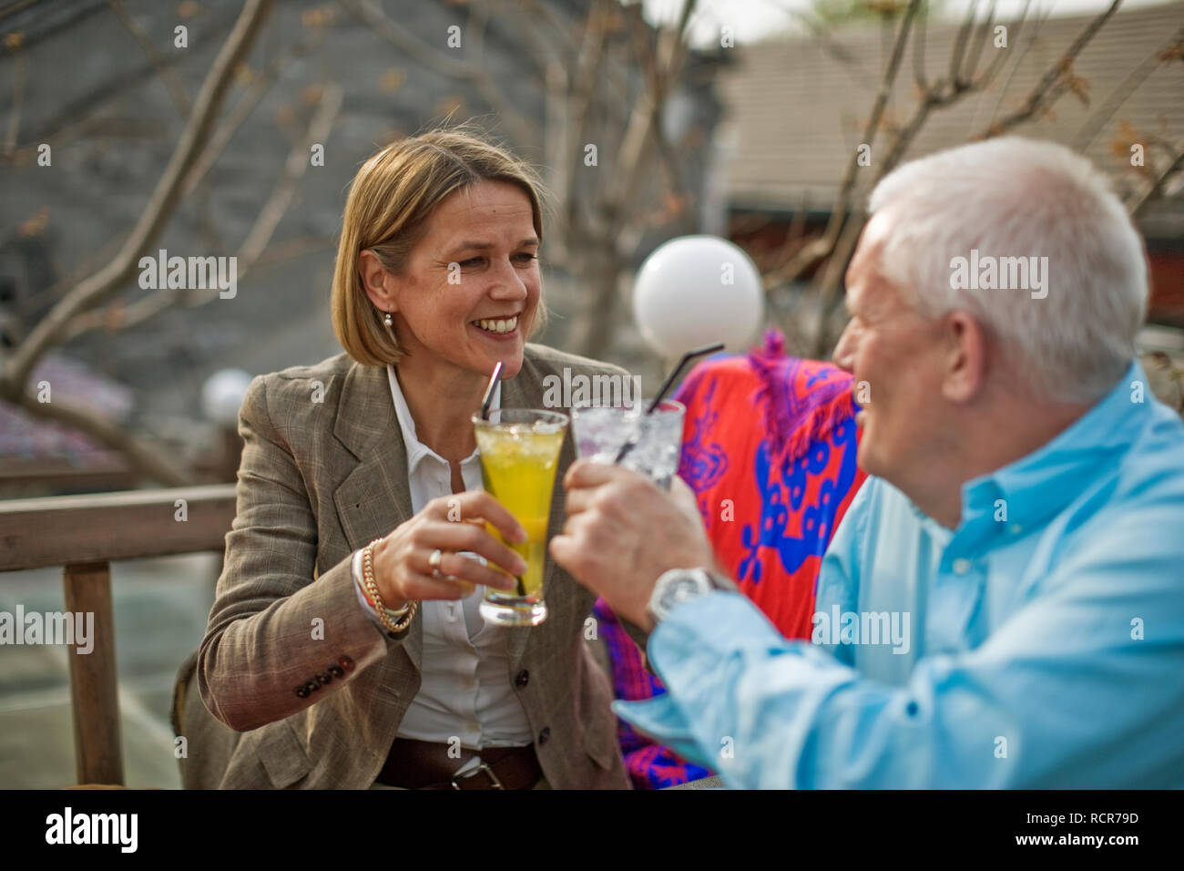 Happy couple smiling at each other while toasting their drinks. Stock Photo