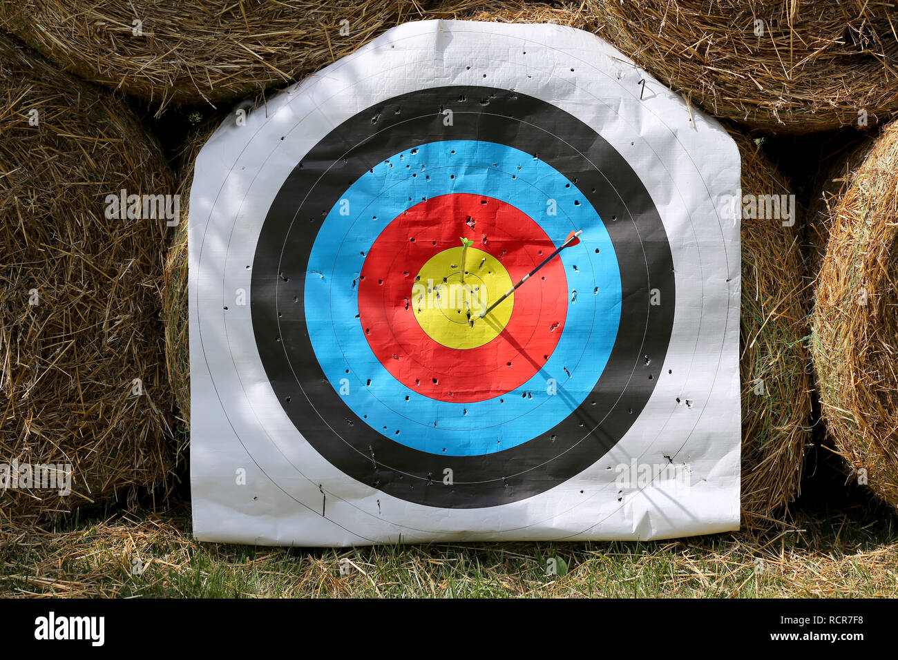 Colorful target template for sport shooting competition. Used target with color circles on shooting range against hay bales Stock Photo