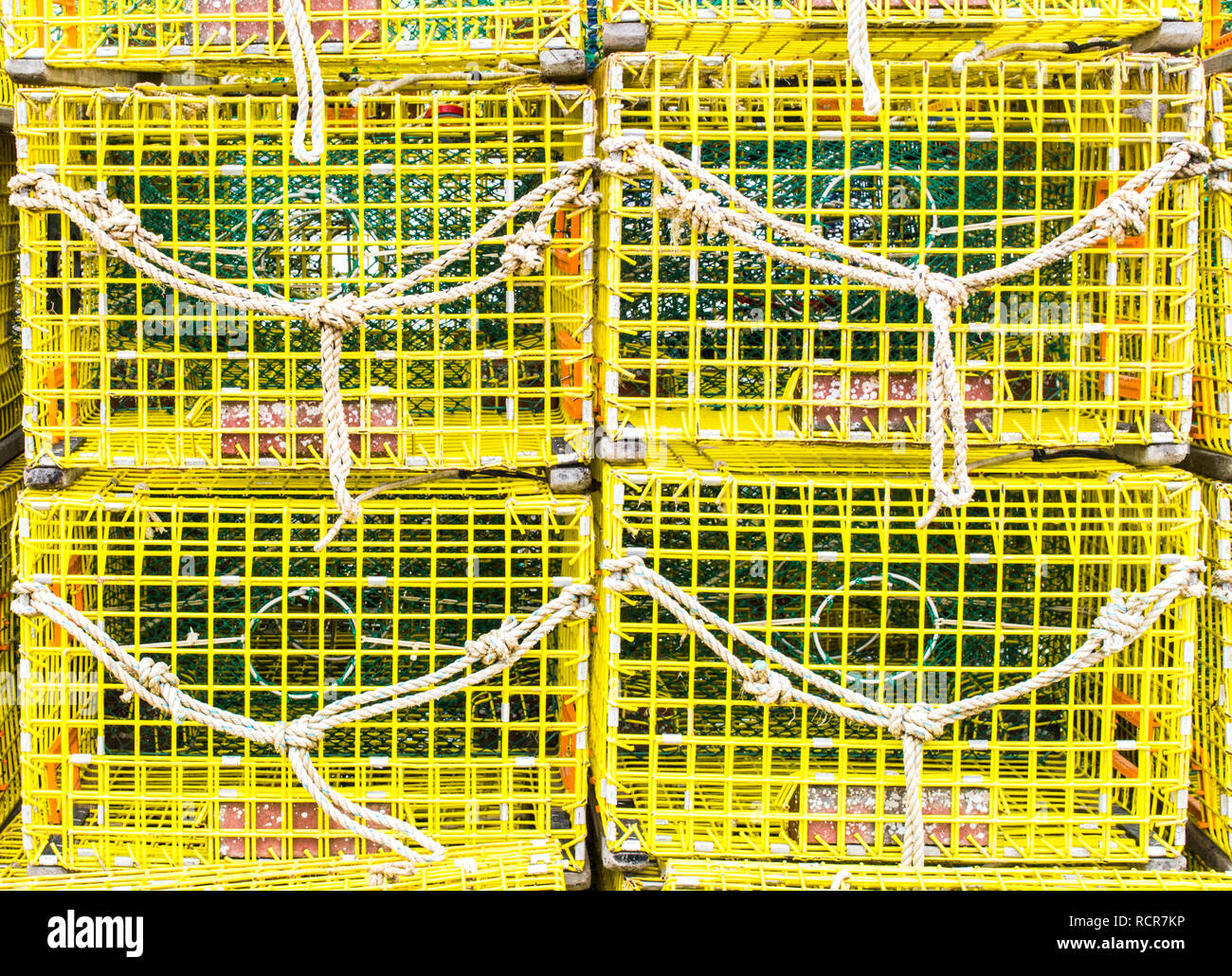 bright yellow empty lobster traps stacked up on a fishing wharf in