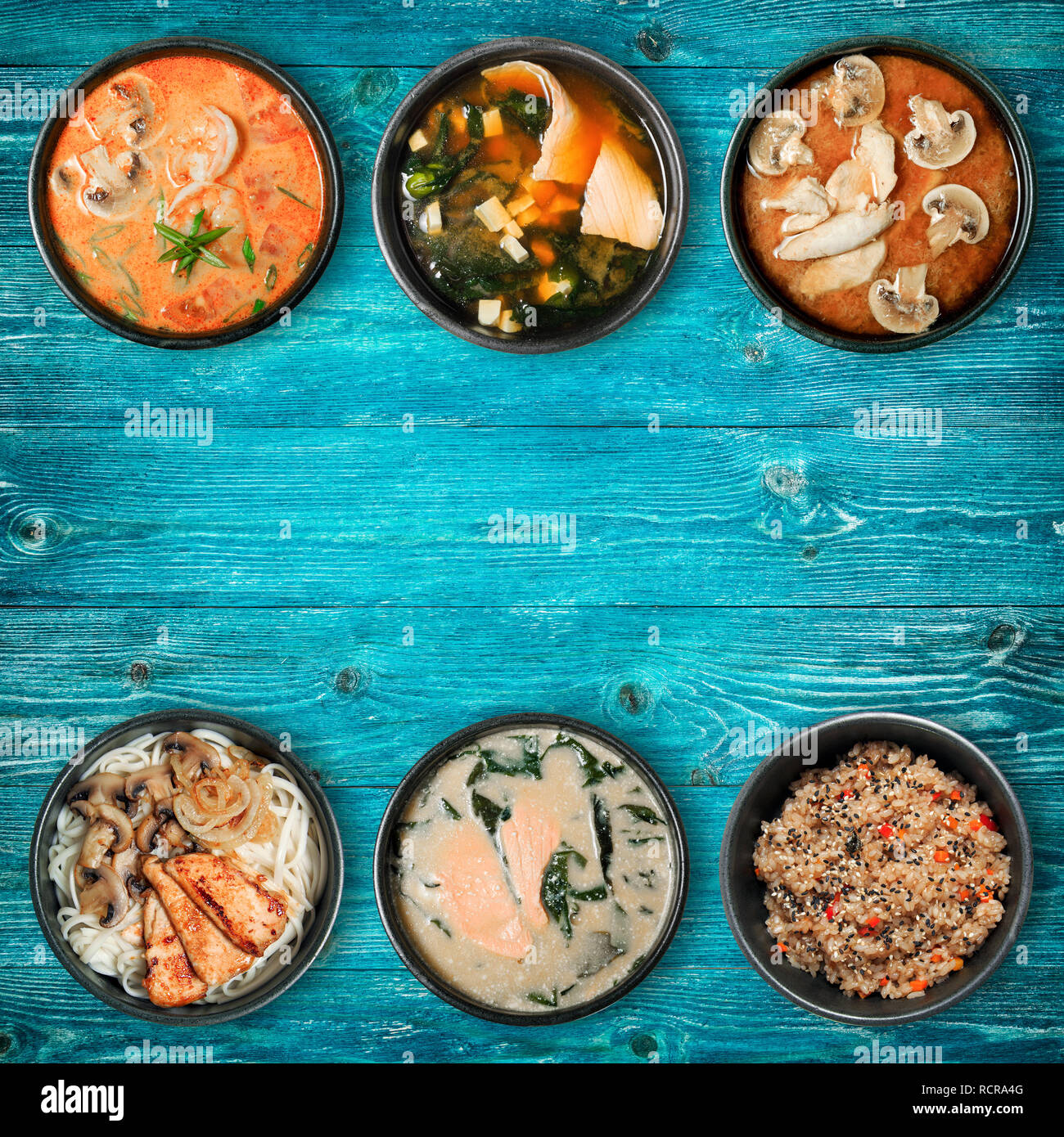 Traditional Asian dishes in black bowls. Wooden blue background with