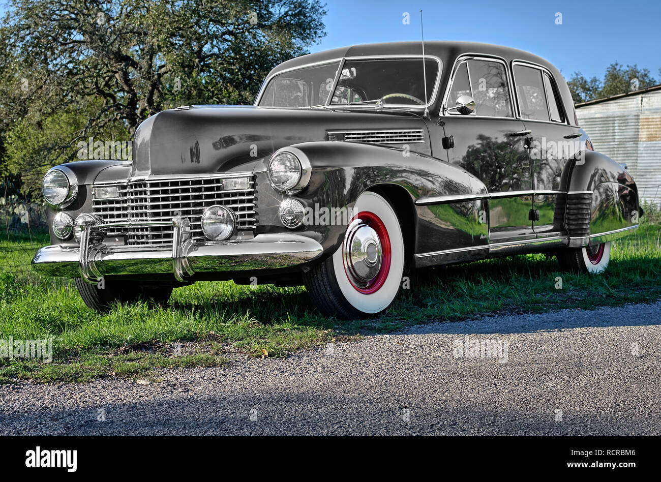 Vintage luxury gray, car with white wall tires and red wheel hubs parked on rural Texas road Stock Photo