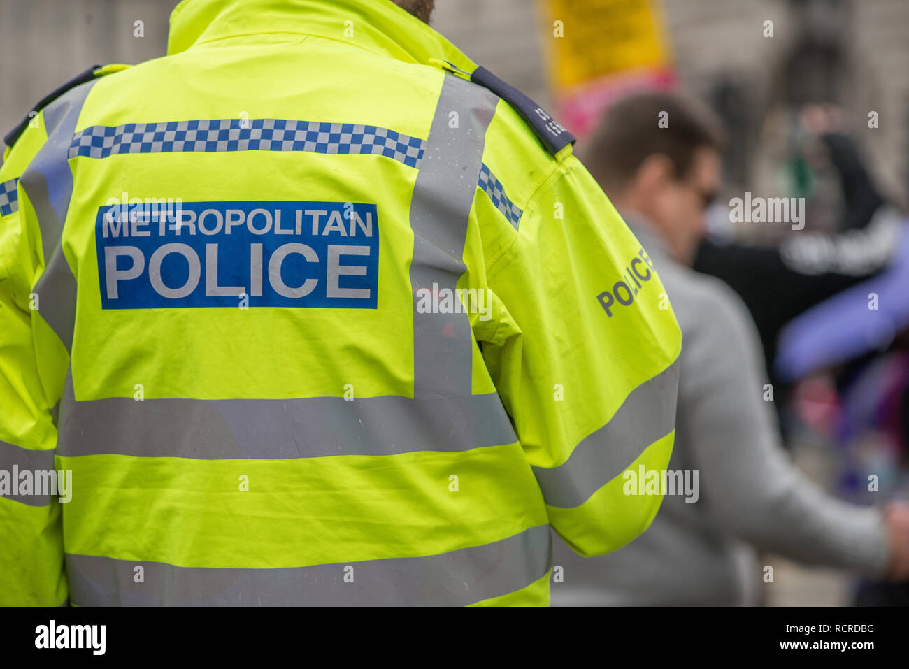 Metropolitan Police sign on the back of a high visibility jacket worn by police officers escorting a street demonstration through central London, UK. Stock Photo