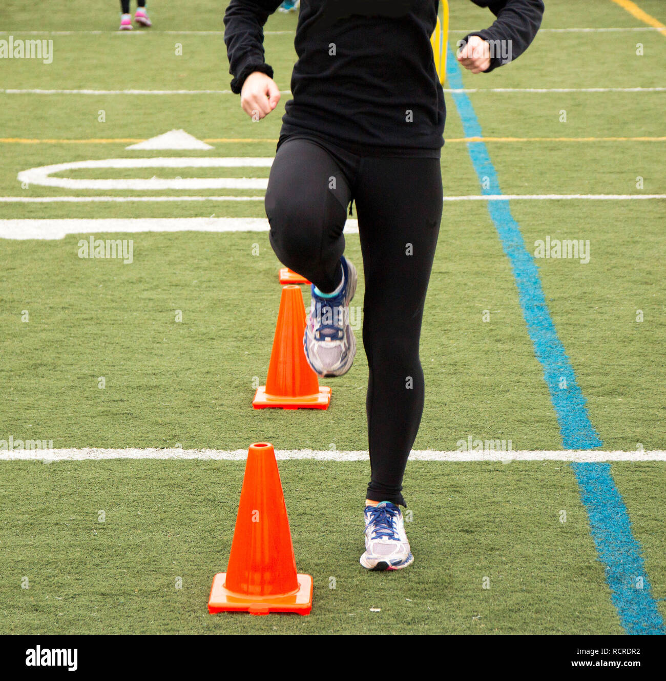 A runner is performing a running drill over orange cones Stock Photo Alamy